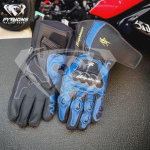 Peut inclure: Gants de moto noirs et bleus avec des coutures blanches. Les gants présentent un logo et un texte Hayabusa. Fabriqués en cuir, ils comportent des protections sur les articulations et les doigts. Conçus pour la course.