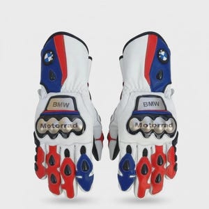 Peut inclure: Une paire de gants de moto blancs, rouges et bleus arborant le logo BMW sur la manchette et l'inscription BMW Motorrad sur la protection des articulations. Les gants présentent des détails noirs, des renforts sur les doigts et une structure.