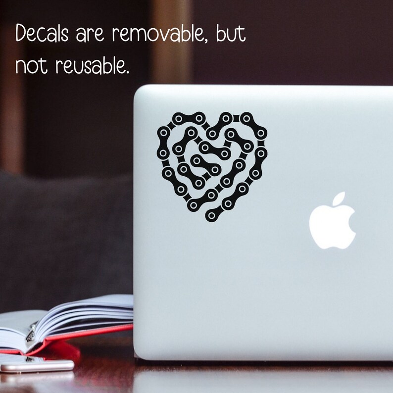 May include: Black and white sticker of a bicycle chain in the shape of a heart. The sticker is on a silver laptop.