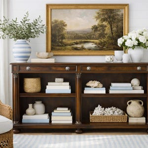 May include: A white ceramic mug with a black handle and the text "But First, Coffee" in a bold, black font. The mug is set against a blurred background, suggesting a cozy setting. The mug appears to be approximately 4 inches tall.