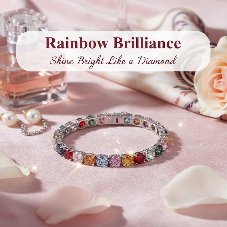 May include: A silver bracelet with a row of colorful gemstones. The bracelet is on a pink surface with a perfume bottle, pearl earrings, and rose petals. Text reads "Rainbow Brilliance Shine Bright Like a Diamond."