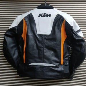 May include: Black, white, and orange leather motorcycle jacket with the KTM logo on the back.