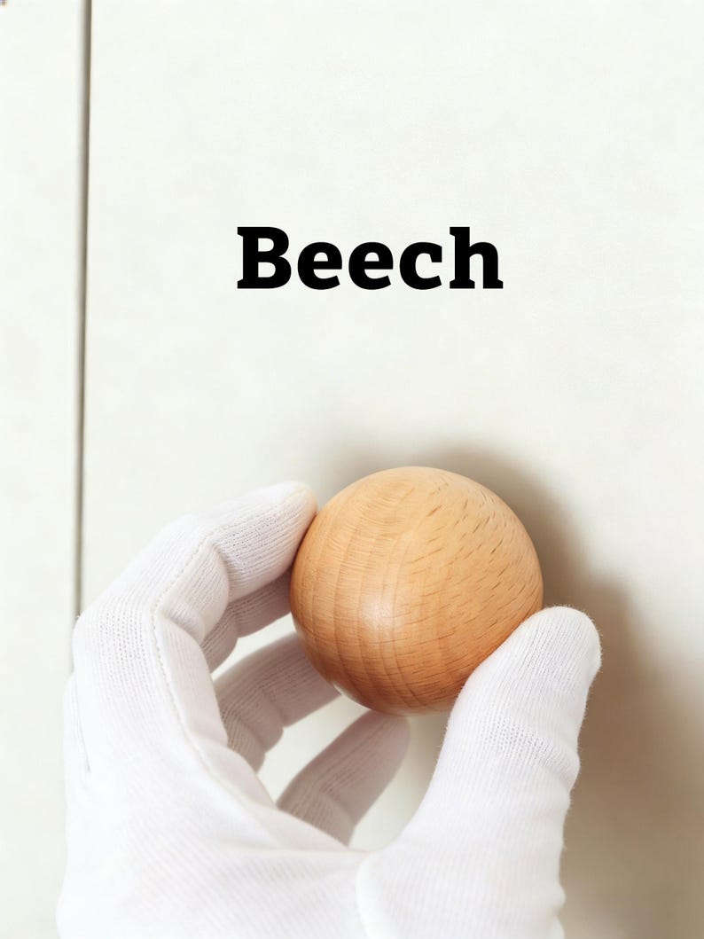 Pu&ograve; includere: Una sfera di legno marrone chiaro tenuta da una mano guantata. La parola "Beech" &egrave; stampata in grassetto nero sopra la sfera. La sfera &egrave; fatta di legno e ha una superficie liscia e lucida.