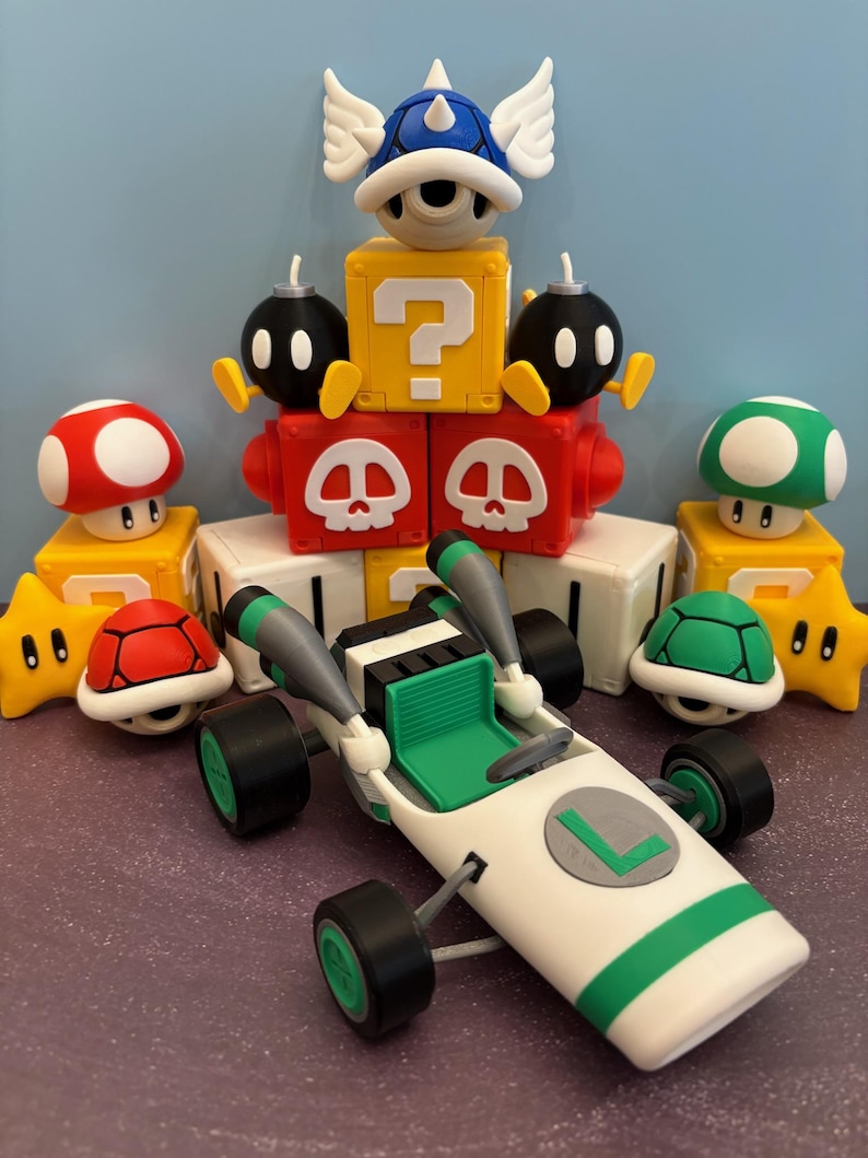 May include: A collection of colorful figurines inspired by a video game. The set includes a white and green race car, a blue shell with wings, mushroom and star figures, and blocks with question marks and skull designs.