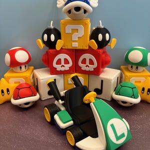 May include: A collection of colorful 3D-printed figures and a kart, inspired by the Super Mario video game series. The kart is black, green, and white, with yellow wheels. Other figures include a red mushroom, a green turtle shell, and a blue shell.