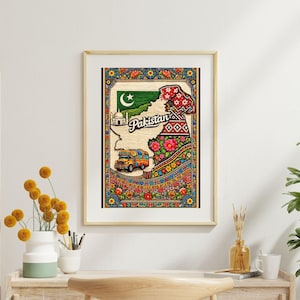 May include: Framed artwork featuring a colorful illustration of Pakistan. The design includes the Pakistani flag, a map outline, and a decorated truck. The artwork is framed in a light wood frame and is displayed on a desk.