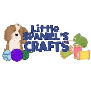 May include: A cartoon illustration of a brown and white spaniel dog with the text "Little Spaniel's Crafts" in blue letters. The image also includes a green chameleon, yarn balls, and spools of thread.