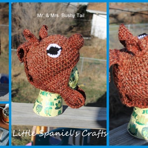 May include: Three crocheted hats shaped like deer heads. The hats are brown with white accents and black eyes. The hats are displayed on mannequins with patterned fabric coverings. The text "Mr. & Mrs. Bushy Tail" and "Little Spaniel's Crafts" are visible in the image.