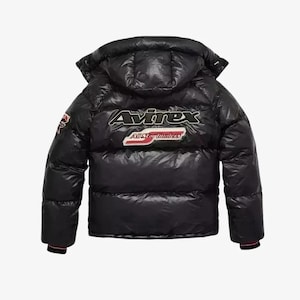 May include: Black puffer jacket with a hood. The jacket features the brand name "Avirex" in white and red lettering on the back, along with a patch that says "All Star Londoners". The jacket has a glossy finish.