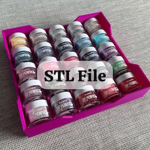 Peut inclure: Un récipient en plastique rose rempli de 20 petits pots de paillettes colorées. Les pots sont étiquetés "Glamour Dip Perfect".