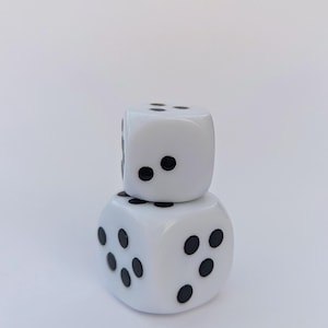 May include: Two white dice stacked on top of each other. Each die has black dots representing numbers. The dice are set against a plain white background.