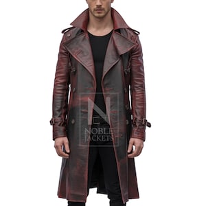 May include: A long, distressed burgundy leather trench coat with a double-breasted design. The coat features a wide collar, shoulder epaulets, and adjustable belt straps. The coat is worn over a black shirt and trousers.