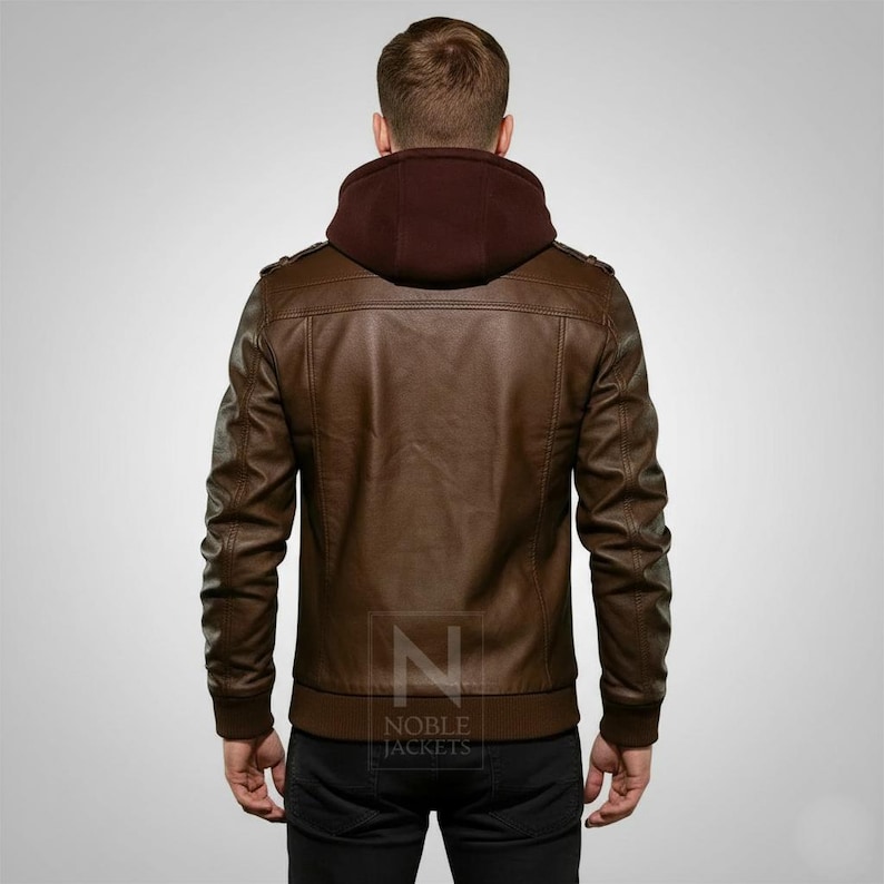 May include: Brown leather jacket with a burgundy hood, featuring a ribbed hem and cuffs. The jacket has a classic design with shoulder accents and a front zipper. The back view showcases the jacket's tailored fit and the "NOBLE JACKETS" logo.