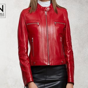 May include: A red leather biker jacket with a zip fastening and multiple pockets. The jacket has a stand-up collar and a slim fit.