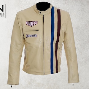 Puede incluir: Chaqueta de cuero color crema con cuello negro y rayas verticales azules y burdeos. Incluye los logotipos "HEUER" y "Firestone". También se ve el logotipo de "Noble Jackets".