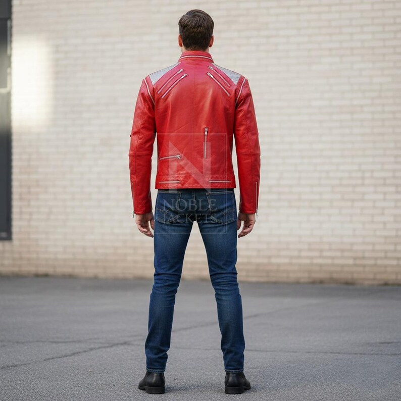 Puede incluir: Chaqueta de cuero roja con detalles plateados en los hombros y m&uacute;ltiples bolsillos con cremallera. Se combina con vaqueros azules y botas negras. En la parte trasera de la chaqueta, se aprecia la marca "NOBLE JACKETS" en los vaqueros.