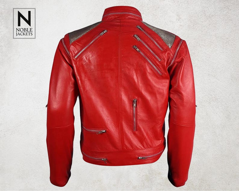 Puede incluir: Chaqueta de cuero rojo brillante con m&uacute;ltiples cremalleras plateadas y cuello alto. Los hombros tienen un panel plateado texturizado. El logotipo "Noble Jackets" est&aacute; en la esquina superior izquierda.