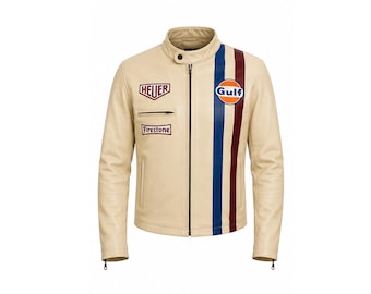 Puede incluir: Una chaqueta de cuero color crema con cremallera central, cuello con botón a presión y dos franjas verticales en azul y rojo oscuro en el lado izquierdo. El pecho presenta un logotipo circular de Gulf, un parche de Heuer y un parche de Firestone.