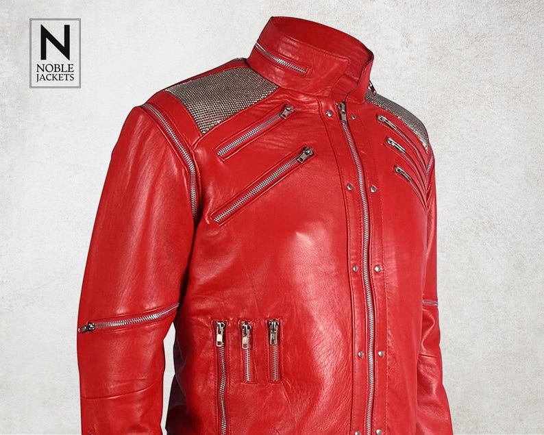 Puede incluir: Chaqueta de cuero roja vibrante con m&uacute;ltiples cremalleras plateadas y cuello alto. La chaqueta presenta un panel plateado texturizado en los hombros. La marca "NOBLE JACKETS" est&aacute; en un recuadro blanco.