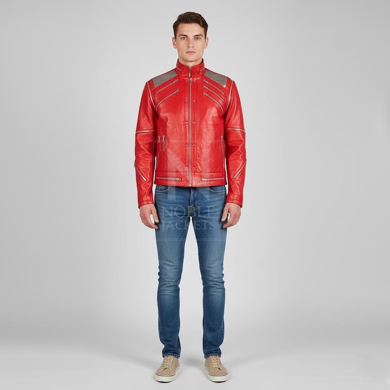 Puede incluir: Chaqueta de cuero roja con detalles plateados en los hombros y las mangas. La chaqueta tiene cierre de cremallera y cuello alto. La persona lleva vaqueros azules y zapatillas de deporte beiges.