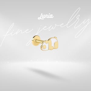 May include: A gold-tone flat back stud earring featuring a panda-shaped charm with white enamel detailing. The jewelry piece includes a circular base and a post. The text Lunia fine jewelry is visible in the background above the earring.