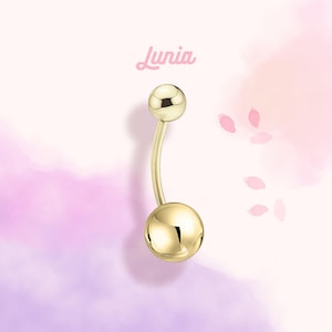 Puede incluir: Anillo de ombligo de oro con dos bolas redondas. El anillo es curvo y tiene un acabado liso.