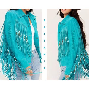 Puede incluir: Una chaqueta de ante color turquesa brillante con largos flecos en las mangas y paneles frontales. Los flecos est&aacute;n decorados con peque&ntilde;as cuentas cil&iacute;ndricas en blanco, marr&oacute;n y azul. La palabra RAFFANIA est&aacute; impresa verticalmente.
