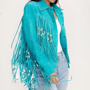 Puede incluir: Una chaqueta de ante color turquesa brillante con largos flecos en las mangas y el pecho. Los flecos est&aacute;n decorados con peque&ntilde;as cuentas de madera y blancas. La chaqueta tiene cuello, cierre frontal de botones y la palabra RAFFANIA impresa.