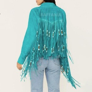 Puede incluir: Una chaqueta de color turquesa brillante con largos flecos en la espalda y las mangas. Los flecos est&aacute;n decorados con peque&ntilde;as cuentas cil&iacute;ndricas en tonos blanco, marr&oacute;n y turquesa. La palabra RAFFANIA est&aacute; impresa en la parte superior trasera.
