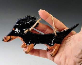 May include: Black and brown ceramic dachshund ornament with a white eye and a string for hanging.