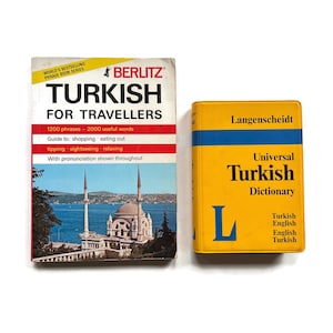 May include: Two books: "Turkish for Travellers" by Berlitz and a "Universal Turkish Dictionary" by Langenscheidt. The Berlitz book has a white cover with red stripes and a photo of a mosque. The dictionary is yellow with blue accents.