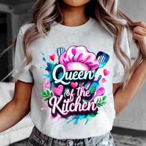May include: White t-shirt with a colorful graphic design. The design features the text "Queen of the Kitchen" in a cursive font, a chef's hat, hearts, and cooking utensils. The design has a watercolor effect with splashes of blue, pink, and green.
