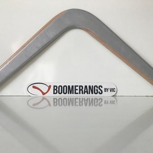 May include: A silver boomerang with a wooden core. The boomerang is made by Boomerangs by Vic.