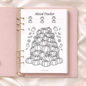 Könnte beinhalten: Ein rosa Ordner mit einer weißen Seite mit einem "Mood Tracker"-Design. Das Design umfasst einen Stapel Kürbisse, Geister und Blätter. Die Seite ist geöffnet und zeigt das Design mit einem weichen, weißen Hintergrund.