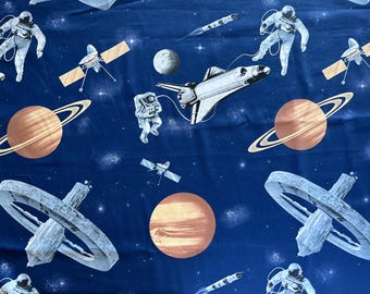 May include: A blue fabric with a space theme featuring astronauts, spaceships, planets, and stars. The fabric has a repeating pattern.