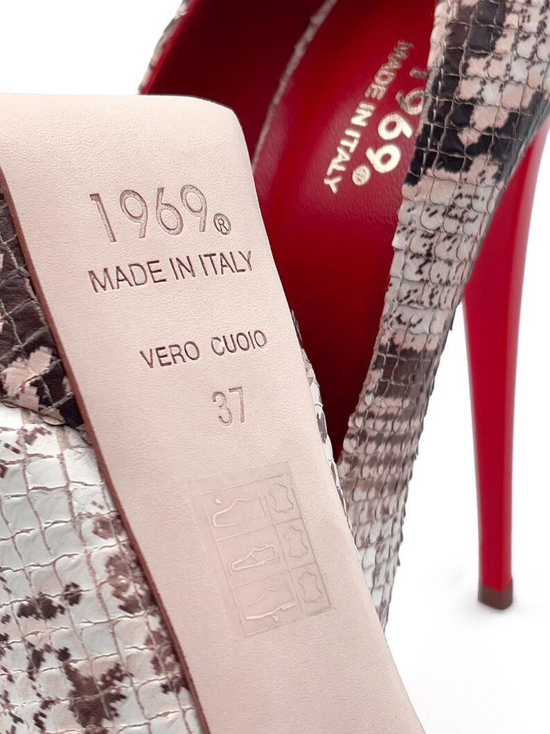 May include: Close-up of a high-heeled shoe with a snakeskin pattern. The sole is red, and the heel is thin. The insole is stamped with "1969 MADE IN ITALY VERO CUOIO" and size 37.