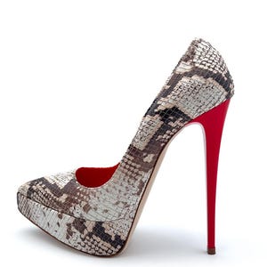 May include: A snakeskin-patterned platform pump with a high stiletto heel. The shoe features a pattern of brown, beige, and black. The heel and interior are a vibrant red. The platform sole adds height and style.