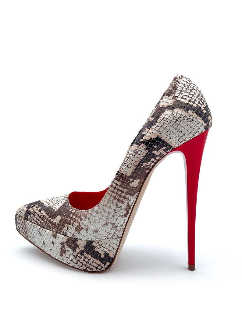 May include: A snakeskin-patterned platform pump with a high stiletto heel. The shoe features a pattern of brown, beige, and black. The heel and interior are a vibrant red. The platform sole adds height and style.
