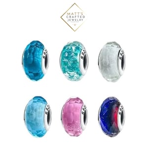 May include: Six colourful glass beads with silver accents. The beads are in shades of blue, teal, white, pink, and a dark blue with red. Each bead has a faceted design and the text "S925" on the silver accent.