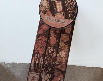 May include: A roll of decorative adhesive tape featuring a dark brown and muted red colour palette. The tape displays intricate illustrations of insects, botanical elements, roses, a gramophone, and framed portraits with the text The Naturalist Lonely Prairie.