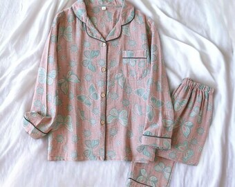 May include: A pink and green pajama set with a butterfly print. The top has long sleeves and a button-up front. The pants have an elastic waistband.