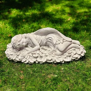 May include: A serene, light-colored garden statue of a sleeping fairy. The fairy is lying on a bed of leaves, with detailed wings and a floral crown. The statue is made of a durable material and is suitable for outdoor display.