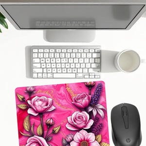 Peut inclure: Tapis de souris floral rose avec un motif de roses, une souris noire, un clavier blanc et un écran d'ordinateur. Le tapis de souris a un fond marbré avec des accents dorés et le texte "Mouse mat floral".