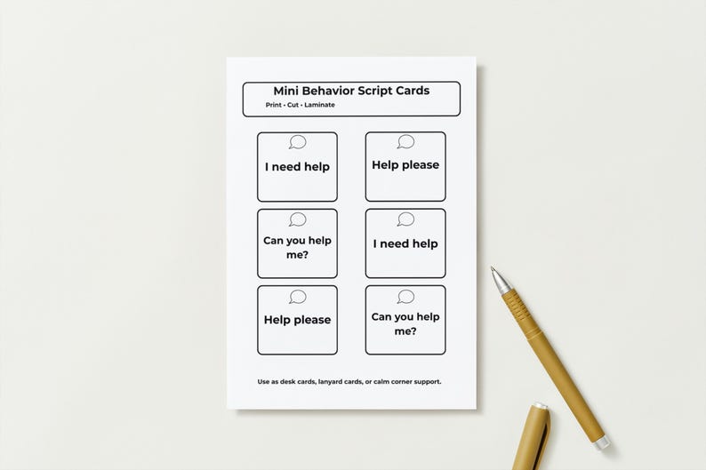 Pu&ograve; includere: Un foglio bianco di Mini Schede di Script Comportamentali con sei caselle, ognuna contenente una frase come "Ho bisogno di aiuto" e "Puoi aiutarmi?" Una penna e un cappuccio dorati sono a destra. Le schede sono per scrivania, cordino o angolo calmo.