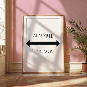 May include: A white framed poster with black text and arrows that reads "This way" and "That way".