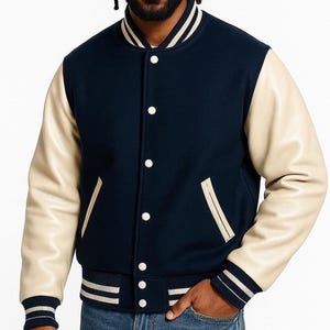 May include: A navy blue varsity jacket with cream leather sleeves. The jacket has white striped detailing on the collar, cuffs, and hem, with white buttons and front pockets. A classic, sporty outerwear garment.