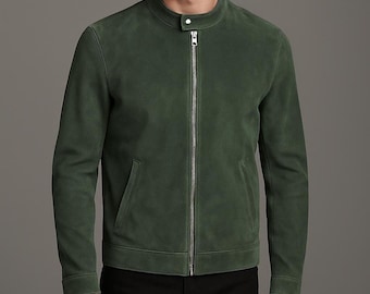 Könnte beinhalten: Eine grüne Wildlederjacke mit Stehkragen und silbernem Reißverschluss. Die Jacke hat zwei Seitentaschen und lange Ärmel. Die Jacke ist einfarbig und aus weichem Material gefertigt.