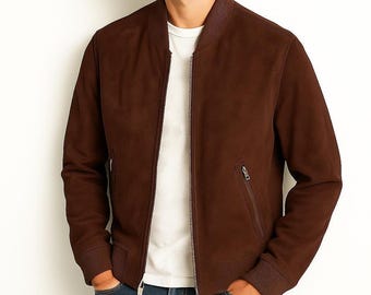 May include: A dark brown bomber jacket with a smooth texture, featuring a ribbed collar, ribbed cuffs, and a full-length front zip. The jacket includes two slanted side pockets with silver-toned zips, worn over a plain white t-shirt and blue jeans.