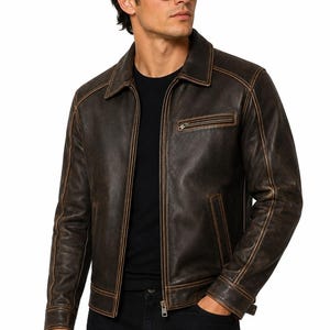 Puede incluir: Una chaqueta de cuero marrón oscuro con acabado desgastado, que presenta un cuello clásico, cierre frontal de cremallera, un bolsillo en el pecho con cremallera y dos bolsillos laterales. La chaqueta tiene costuras visibles en las uniones.