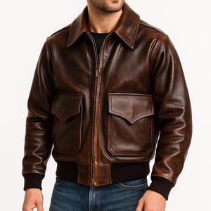 May include: A brown leather bomber jacket with a wide collar, two front pockets, and a zip closure. The jacket has a ribbed hem and cuffs. The leather has a distressed appearance.